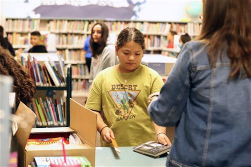 Student checking out library book at Knickrehm media center